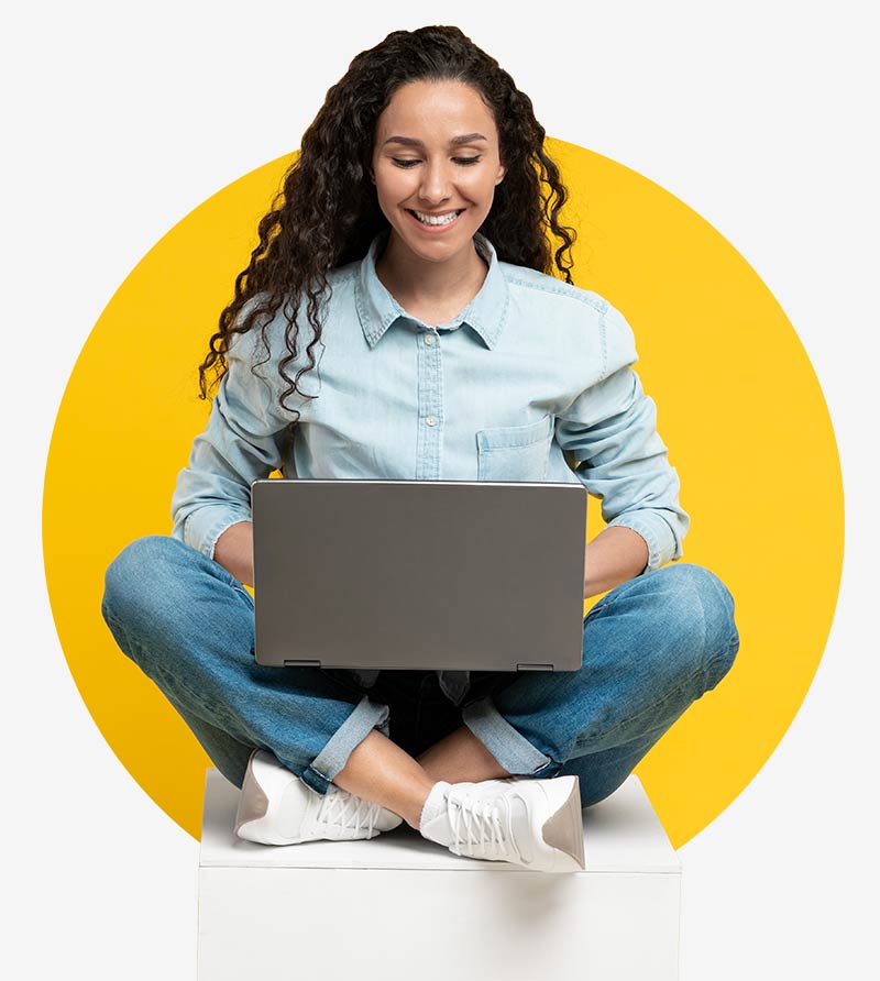 A woman sits cross-legged looking at her laptop - she is pleased with the range of CRM industry solutions from awisto and the many Dynamics 365 CE reference customers.