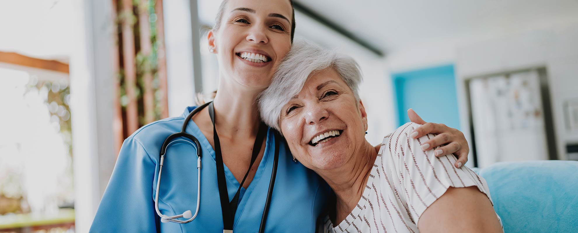 Nurse warmly and happily embraces a cheerful elderly lady in a care facility of the Evangelische Heimstiftung.